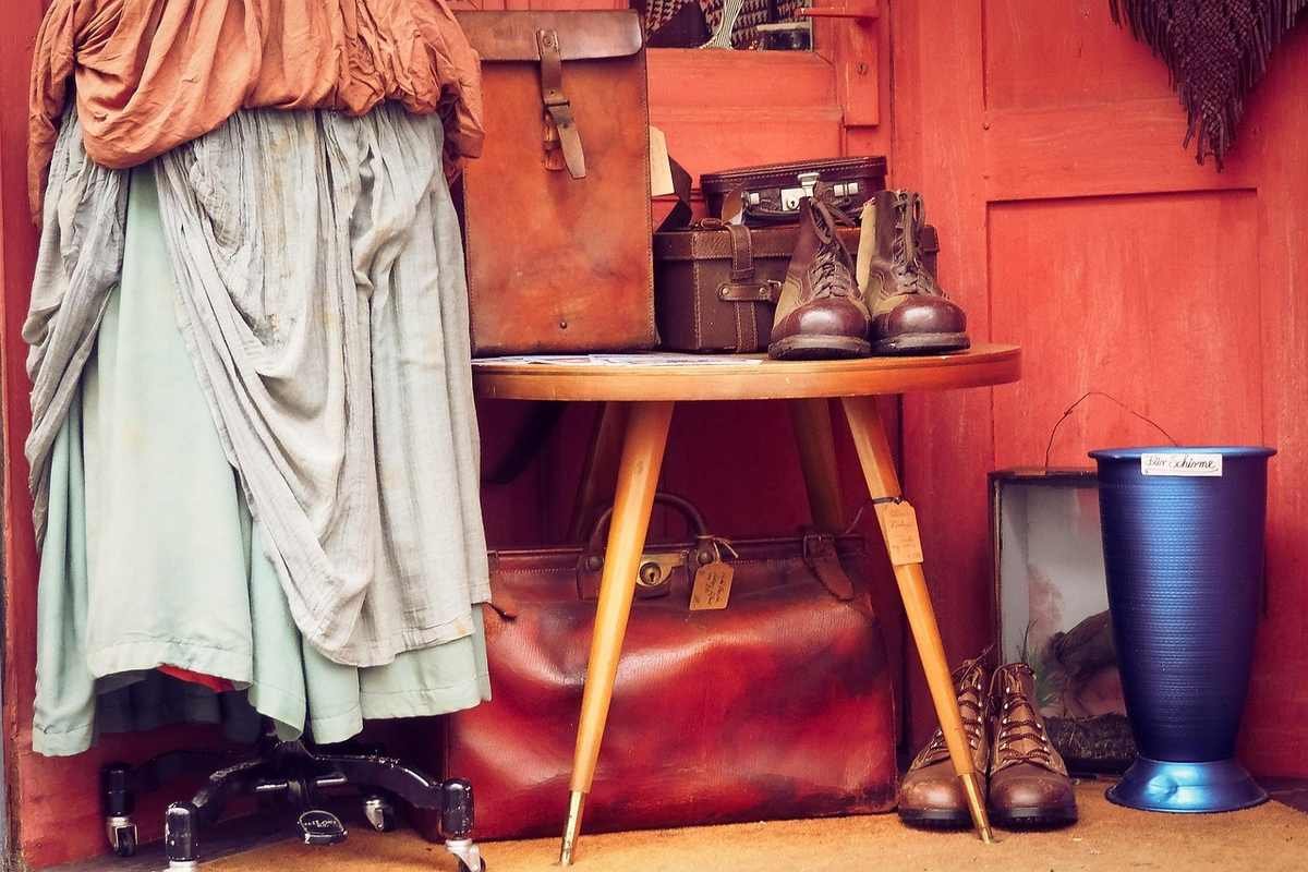 Table en bois avec bagages et bottes, robe sur chaise à roulettes, mur orange