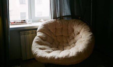 Fauteuil rond rembourré à côté d'une fenêtre avec radiateur et rideaux