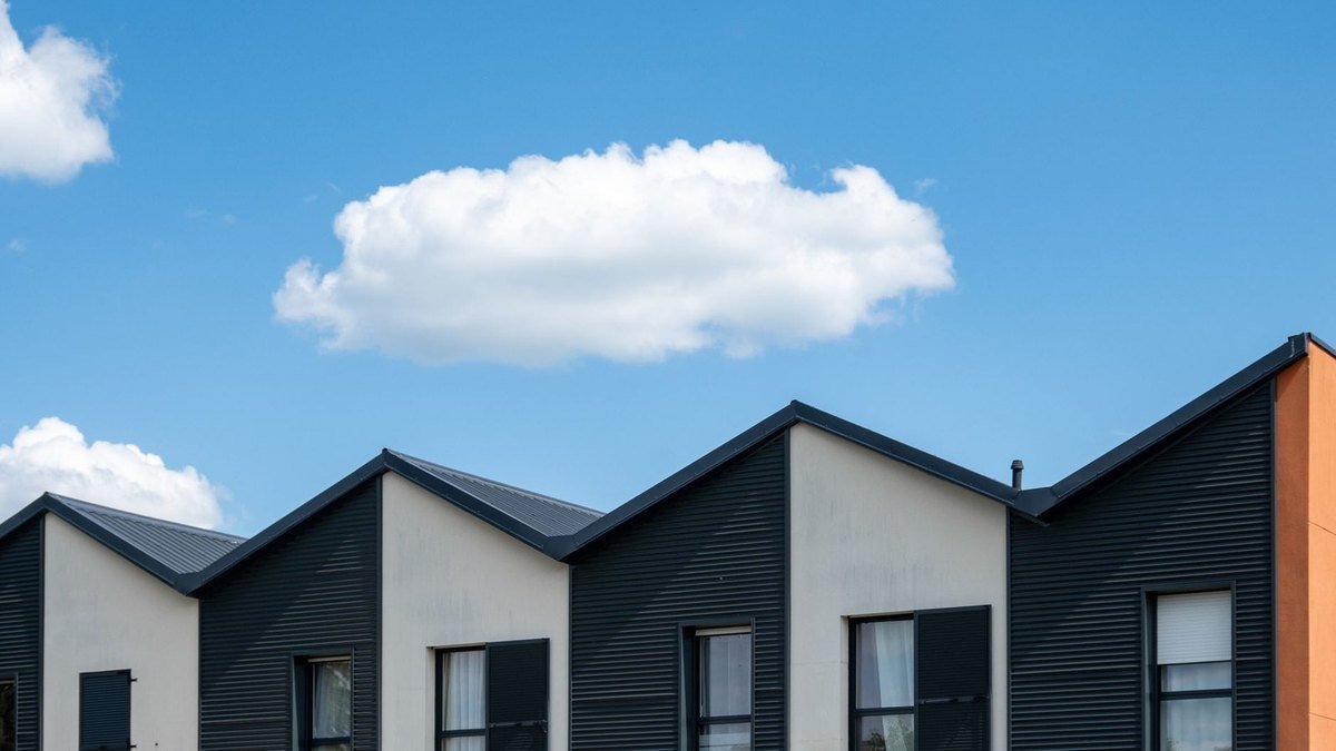 Modern houses with black and white facades, pitched roofs, and windows under a clear sky Modern houses with black and white facades, pitched roofs, and windows under a clear sky